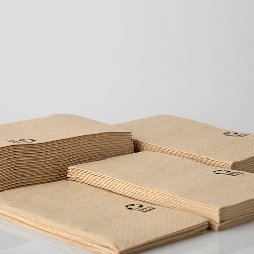 Stapelweise PAPSTAR 3-lagige 1/8-Falz Servietten aus recyceltem Papier (33x33 cm, natur, 100 Stück) liegen auf einer weißen Fläche. Jede umweltfreundliche Serviette trägt ein kleines schwarzes Recycling-Symbol. Der Hintergrund ist schlicht und hell.