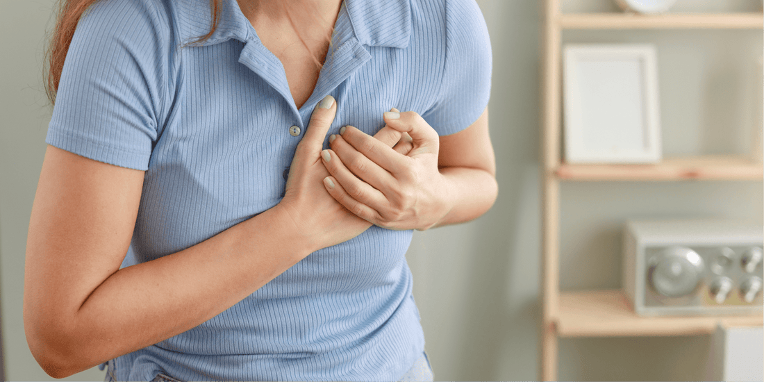 Frau hält sich wegen Brustschmerzen an die Brust – Symbolbild für Herzinfarkt bei Frauen