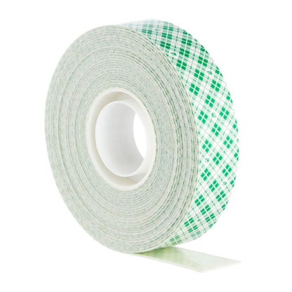 Scotch-FIX™ Dvojstranná interiérová montážna páska od 3M Deutschland GmbH má biely jadro so zeleným kockovaným vzorom a je zobrazená vzpriamene s malou časťou lepiacej pásky.
