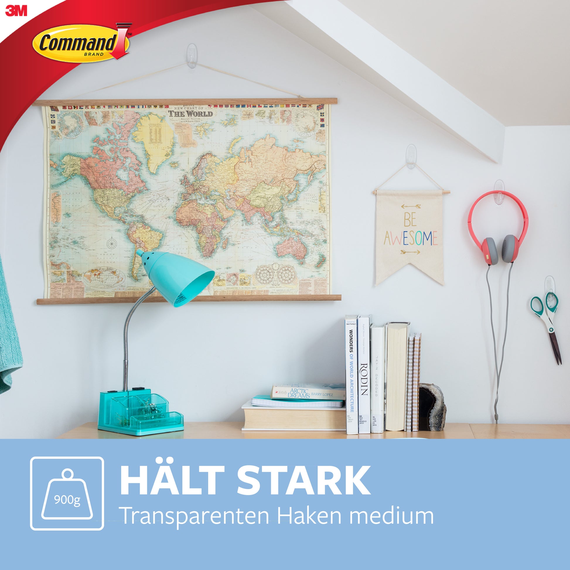 Ein aufgeräumter Arbeitsplatz zeigt eine Weltkarte, ein "Be Awesome"-Schild, Kopfhörer, eine Schere und eine Schreibtischlampe - alles organisiert mit Command™ Haken M, mittelgroß, transparent von 3M Deutschland GmbH. Text unten: "HÄLT STARK Transparenten Haken medium.