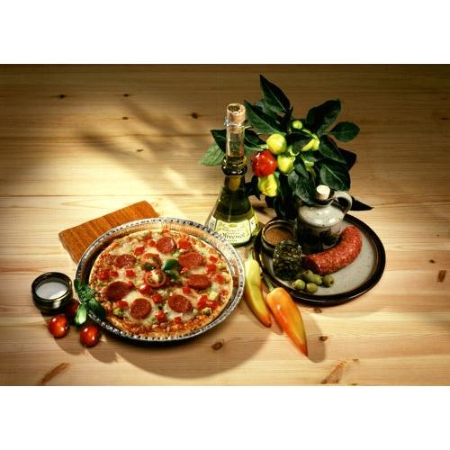 Eine Peperonipizza liegt auf einem Teller neben Weißwein, Wurst und Oliven – frisch gebacken in Starpak 25 Rundformen Alu rund von Starpak für optimale Wärmeleitung – begleitet von Tomaten, Paprika und einer Topfpflanze auf einem Holztisch.