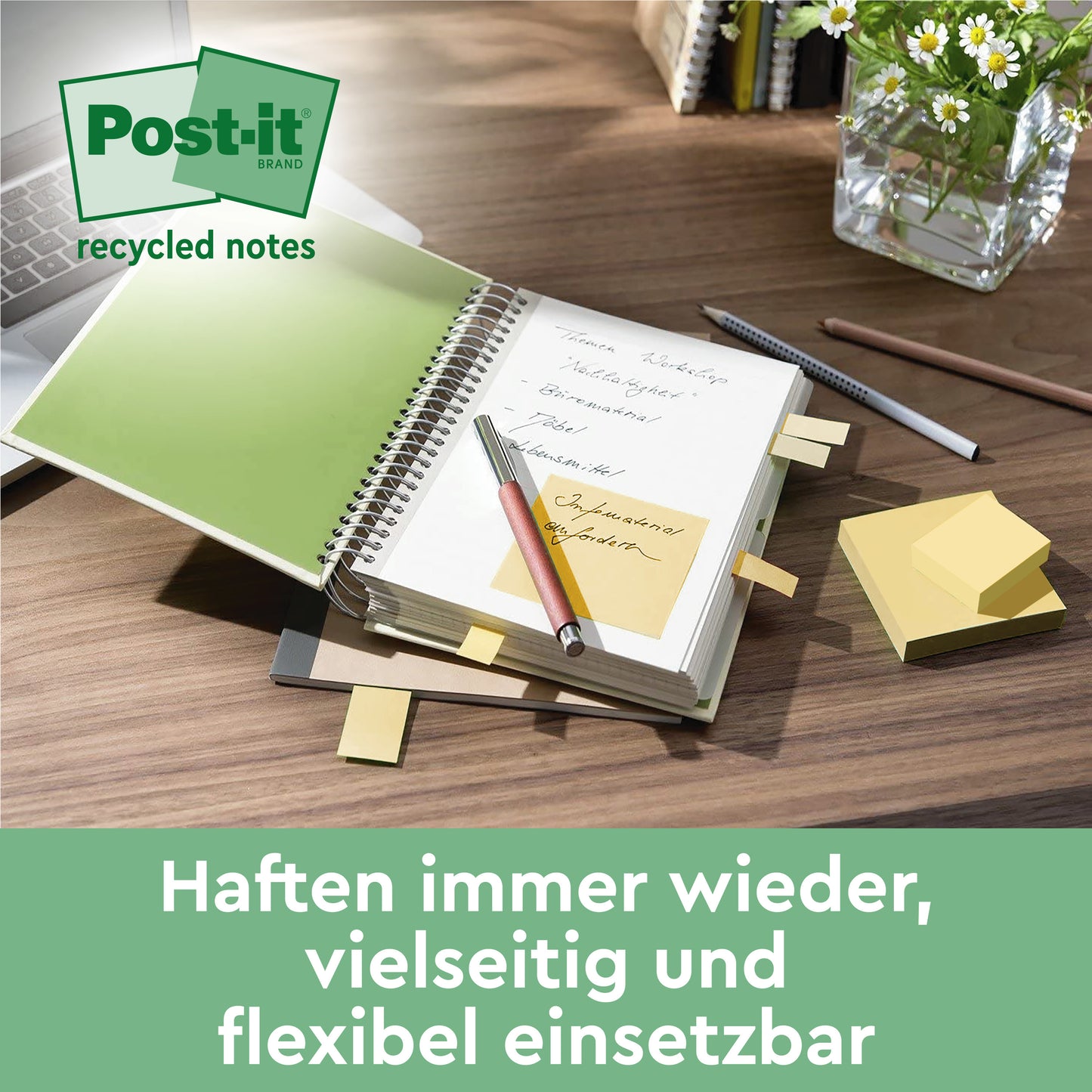 Stôl s otvoreným zápisníkom, niekoľkými žltými Post-it® Super Sticky 100% recyklovateľnými poznámkami (47,6 x 47,6 mm) od 3M Deutschland GmbH, ktoré sú pripevnené na stránkach, perom, hromadou týchto PEFC-certifikovaných poznámok (70 listov/blok) a kvetináčom.