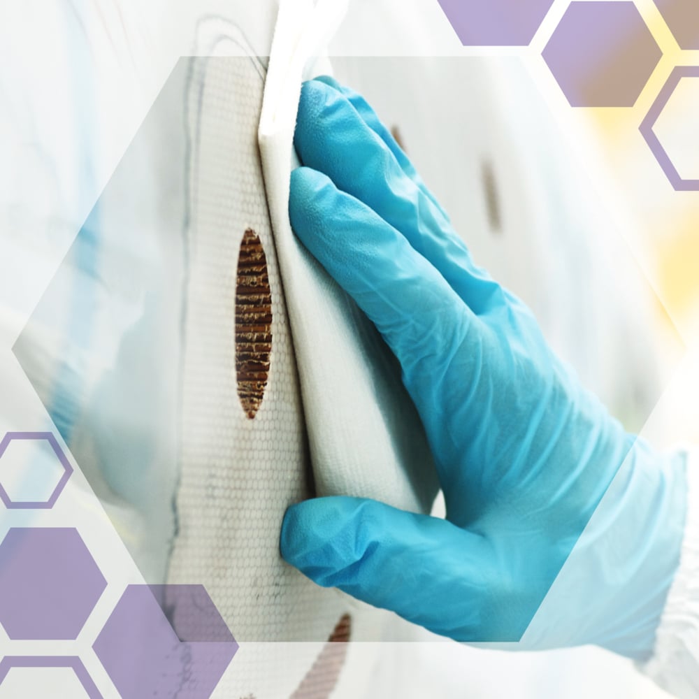 Ruka v rukavici čistí kruhovú hnedú škvrnu na bielom povrchu s precíznymi utierkami Kimtech® Science od Kimberly-Clark GmbH. Polopriehľadné šesťuholníky sú položené cez obrázok.