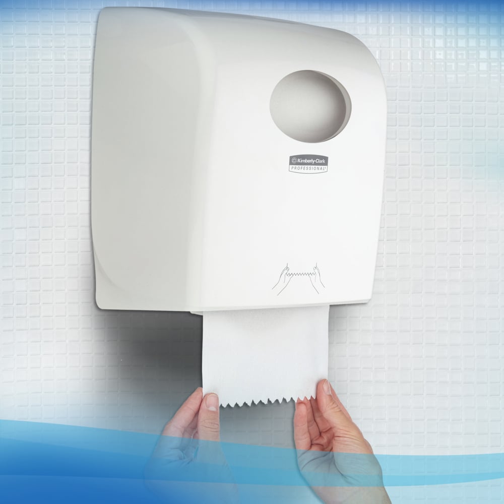 Osoba vyťahuje Scott® Control™ utierku - rolka / biela z bieleho nástenného zásobníka Kimberly-Clark GmbH na toalete s obloženými stenami, čím zabezpečuje hygienické sušenie rúk.