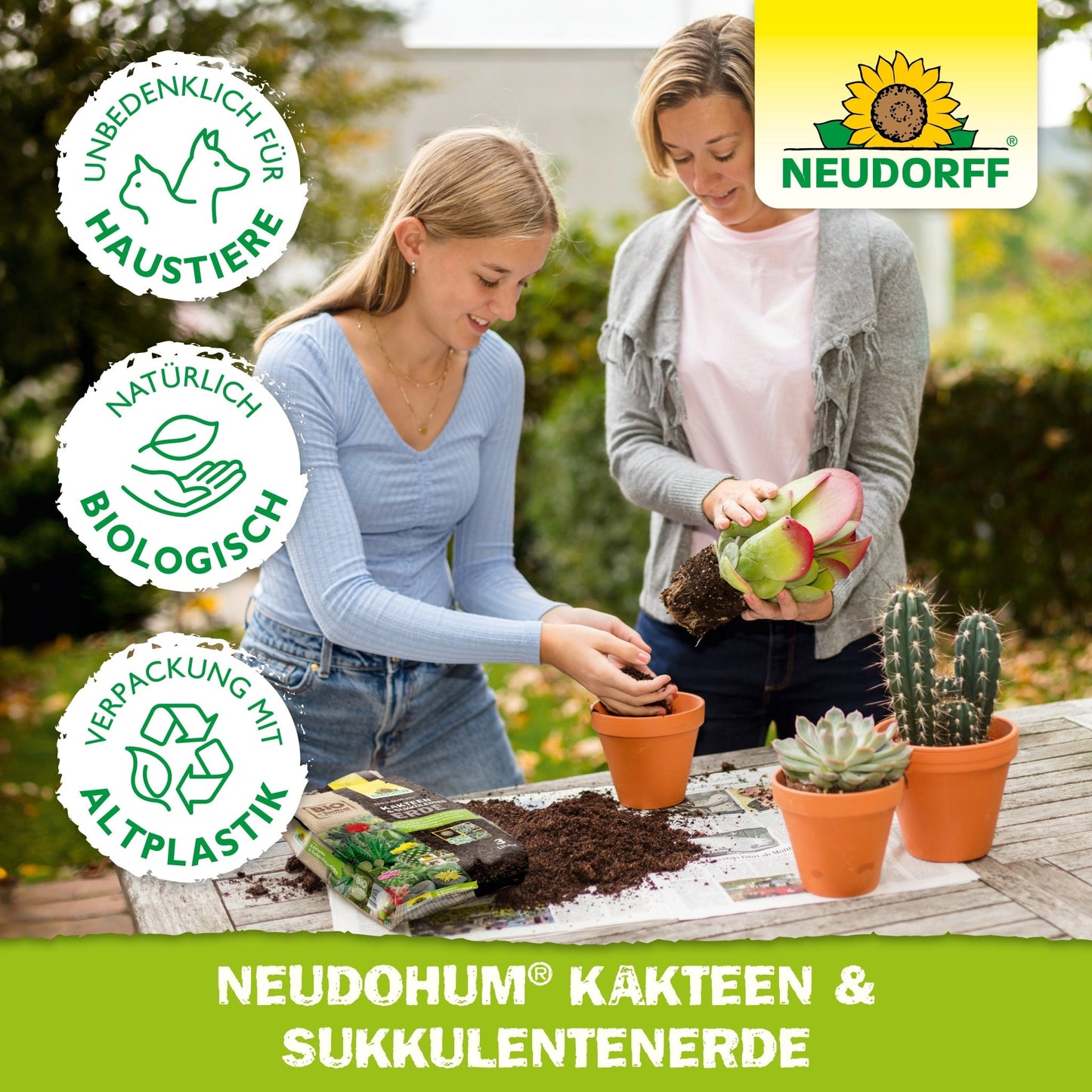 Dve ženy pri presádzaní kaktusov v oranžových kvetináčoch s kvalitnou zeminou na stole, za použitia NeudoHum Kakteen & SukkulentenErde z Neudorff Shop; vlastnosti produktu sú zobrazené v nemeckom texte a symboloch.