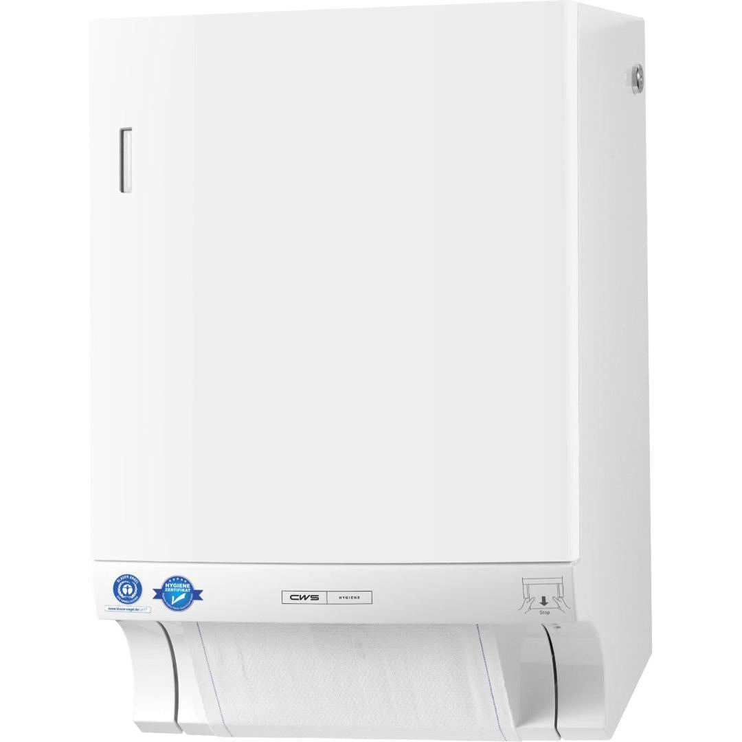 Biely dávkovač látkových uterákov CWS ParadiseLine Dry Slim vrátane panelu so štíhlym dizajnom je pripevnený na stene a ukazuje čiastočne vybratý list na spodku. Modré nálepky, malý strieborný štítok a ilustrovaný návod sa nachádzajú v blízkosti spodku.