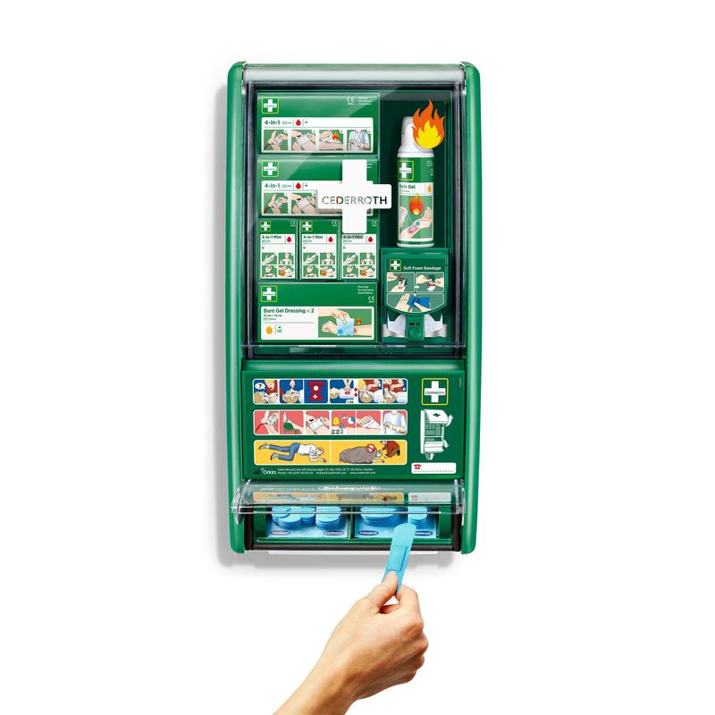 Zelená stanica prvej pomoci a popálenín Cederroth od Orkla Wound Care AB je namontovaná na bielej stene, vybavená obväzmi, gélom na popáleniny, výplachom očí a ďalšími. Ruka vyťahuje modrú lepiacu pásku z dolného dávkovača 1-kusového balenia.