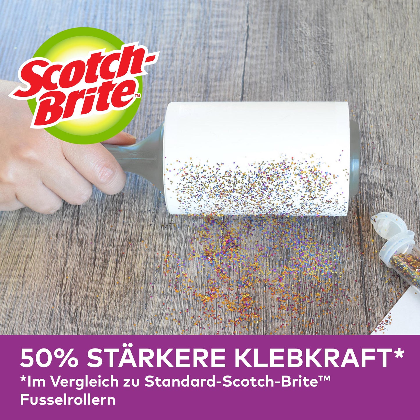 Ruka používa náhradnú rolku na zvieracie chlpy Scotch-Brite™ Pet Extra Sticky* (48 listov, 1/balenie) od 3M Deutschland GmbH na odstránenie rozsypaných trblietok z dreva. Otvorený kontajner s trblietkami je nablízku. "50% silnejšia priľnavosť" v porovnaní so štandardnými rolkami zobrazenými nižšie.