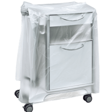 Biely lekársky nočný stolík na kolieskach je čiastočne zakrytý priehľadným krytom na nočný stolík DEISS 59867 (600+500x1000x0,01 mm) od spoločnosti EMIL DEISS KG, ktorý zakrýva zásuvky a úchyty. Pozadie je jednoduché a neutrálne.