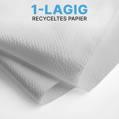 Detailný záber dvoch bielych ARNOMED PAPIEROVÝCH UTIEROK (25 x 23 cm, V-SKLAD) od ARNOWA GmbH so štruktúrovaným povrchom, uložených v V-sklade. Modro-čierny text znie "1-VRSTVOVÝ RECYKLOVANÝ PAPIER" - ideálne pre umyvárne.