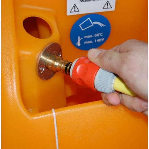 Ruka spája hadicu s červeným a šedým konektorom s kovovou armatúrou na oranžovom TASKI swingo 2100 ?icro AquaStop od Diversey Deutschland GmbH & Co. OHG. Modrá nálepka v blízkosti ukazuje maximálnu teplotu 60°C/140°F.