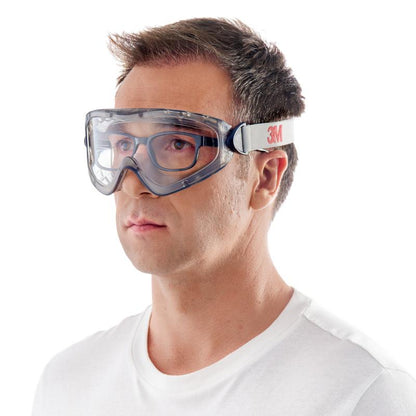 Muž s krátkymi hnedými vlasmi a jednoduchým bielym tričkom nosí pred bielym pozadím 3M™ ochranné okuliare 2890, zapečatené, s čírym sklom od 3M Deutschland GmbH s bielym gumeným pásom s nápisom "3M.