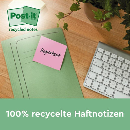 Ružový Post-it® recyklačný lístok (76 x 76 mm, 100 listov, 100% PEFC) od 3M Deutschland GmbH s nápisom "dôležité" je pripevnený na zelenom zakladači na stole vedľa klávesnice a rastliny. Text: "100% recyklované lepiace poznámky."