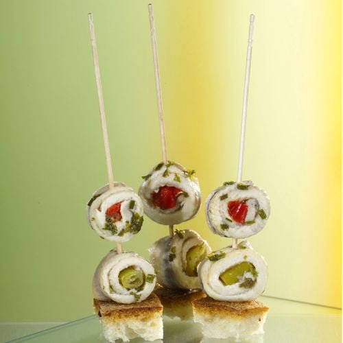 Tri zvinuté rybie filety na špíze stoja zvislo na kockách chleba, prezentované ako PAPSTAR Fingerfood-palička "pure" 15 cm (vyrezávaná, elegantná) od PAPSTAR GmbH - ideálne pre štýlové cateringové udalosti.
