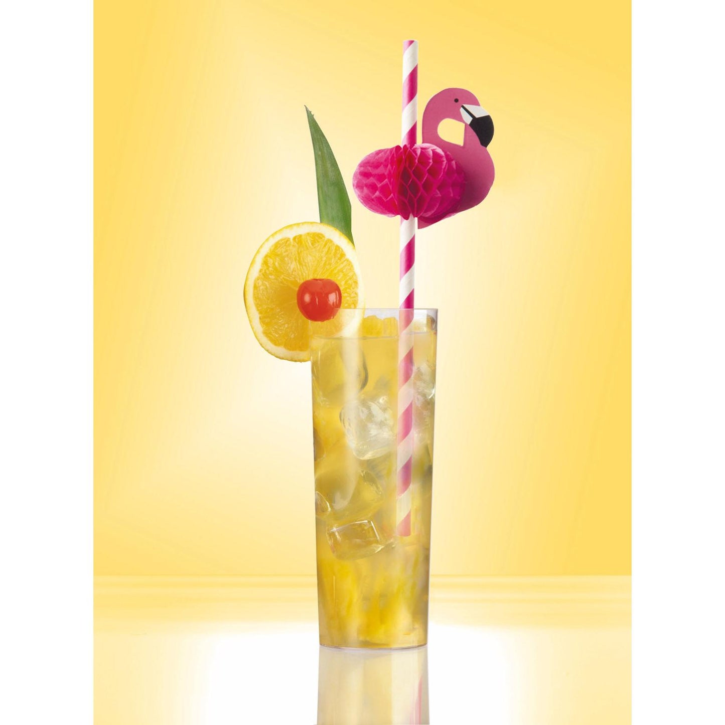 Vysoký pohár so žltým nápojom s ľadom, ozdobený plátkom citróna, čerešňou, zeleným listom a ružovo pruhovanou PAPSTAR papierovou slamkou (6 mm x 20 cm) s ružovým papierovým plameniakom na žltom pozadí. Značka: PAPSTAR GmbH.