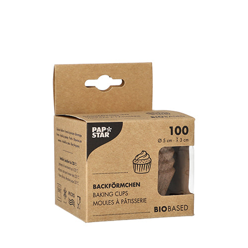 Hnedá škatuľa PAPSTAR GmbH s nápisom „PAPSTAR 100 okrúhlych košíčkov na pečenie“ obsahuje 100 biobázovaných košíčkov na pečenie (5 x 3 cm). Predná strana zobrazuje ilustráciu cupcake, trojjazyčný názov produktu a okienko, ktoré ukazuje košíčky vo vnútri.