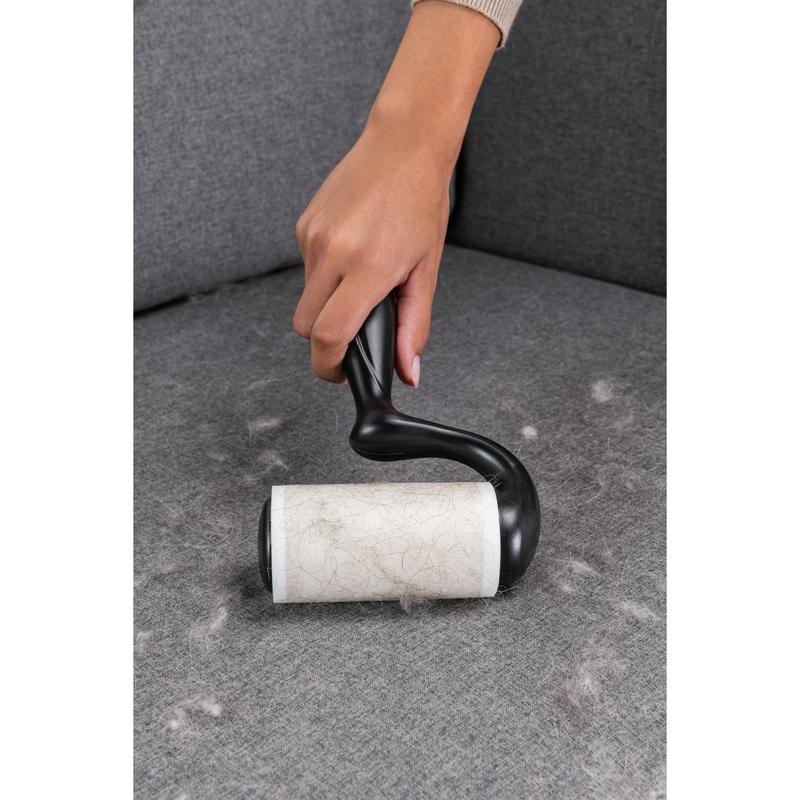 Ruka používa Scotch-Brite™ Everyday Clean Fusselroller na ploché povrchy, 56 listov (3M Deutschland GmbH), na odstránenie zvieracích chlpov zo sivej pohovky a udržanie povrchov čistých.