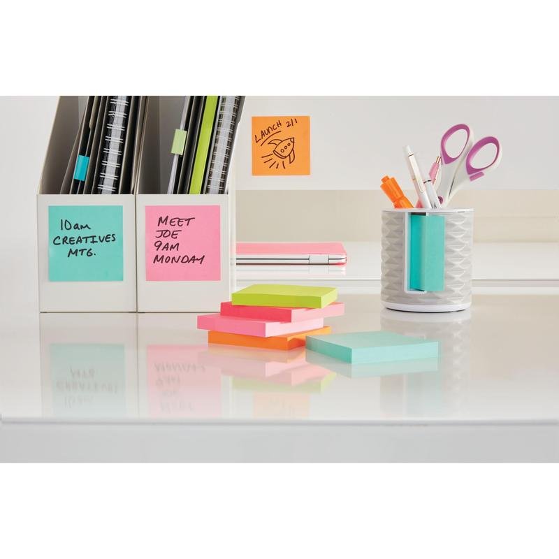 Uprataný stôl s farebnými kockami Post-it® Notes (76x76mm, 450 listov/blok, 100% PEFC) od 3M Deutschland GmbH, bielym stojanom na perá plným pier a nožníc, poznámkovými blokmi a kartotékami. Poznámky sú opatrené ručne písanými pripomienkami.