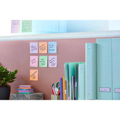 Eine rosafarbene Wand mit Post-it® Super Sticky Notes (47,6 x 47,6 mm, 90 Blatt, 100% PEFC) der 3M Deutschland GmbH, eine grüne Pflanze, eine gemusterte Schachtel, eine Schere, geordnete Ordner auf dem Schreibtisch und weitere Notizen auf einer Glasplatte darüber.