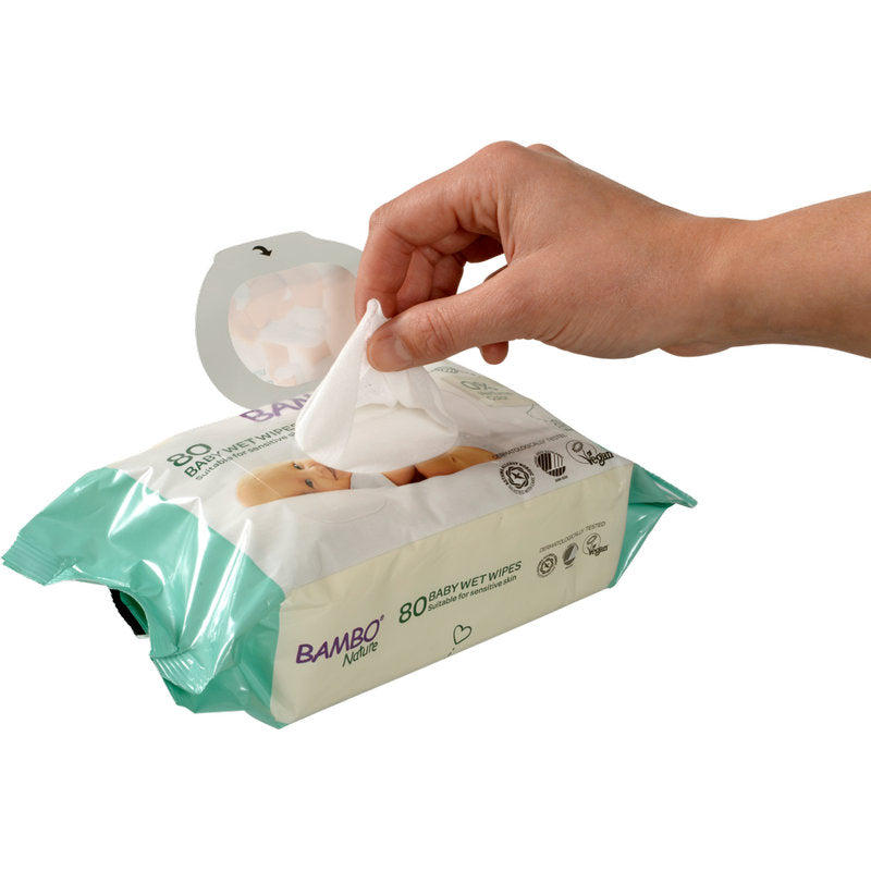 Eine Hand zieht ein Abena Re-Seller GmbH Bambo Nature Feuchtpflegetücher m. Klebeverschluss, 15x20cm (80 Paare) aus einer weiß-grünen Verpackung, die mit Produktinfos und Symbolen beschriftet ist.