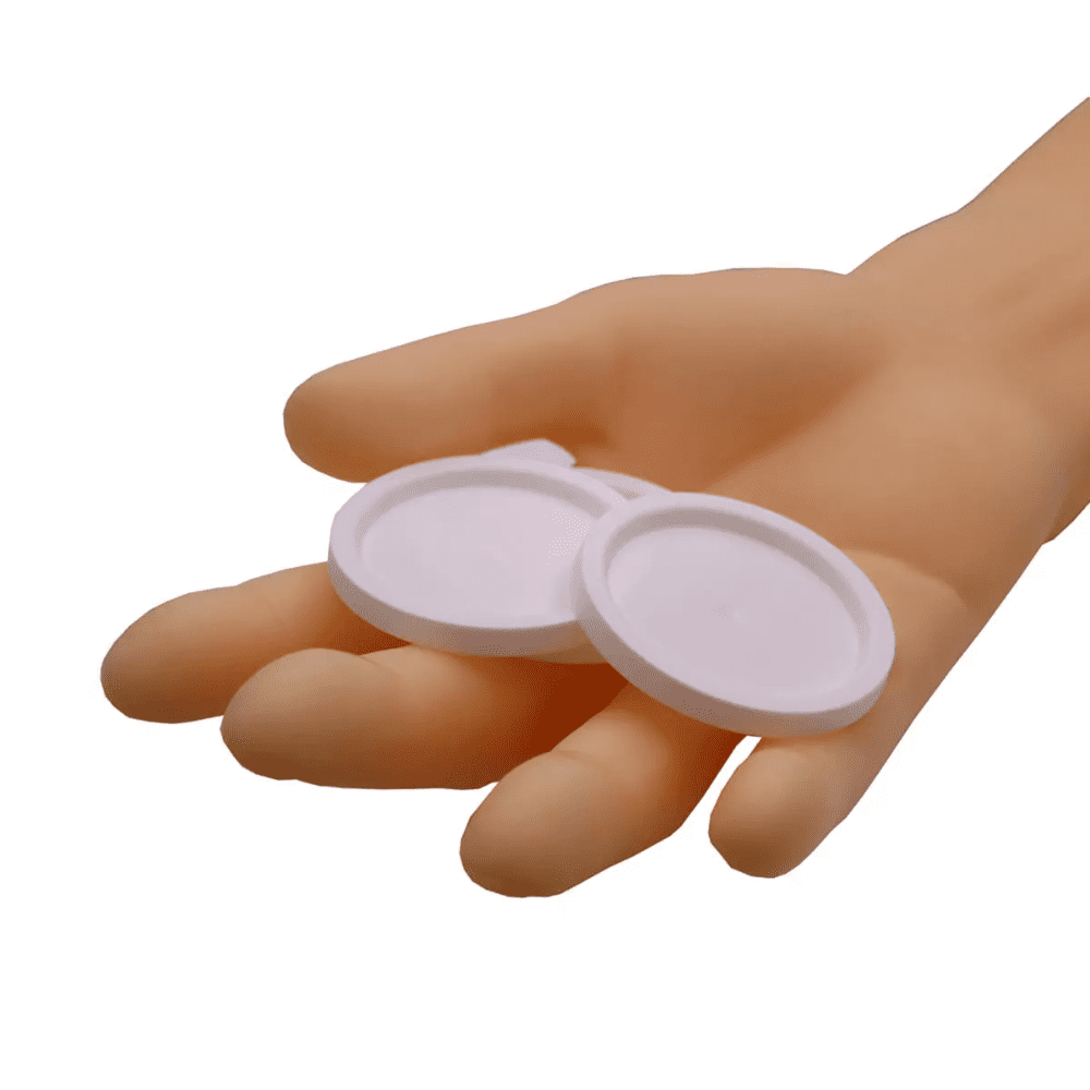 Jedna ruka drží dva okrúhle AMPri viečka pre medicínske poháre, biele objekty na jednoduchom bielom pozadí.