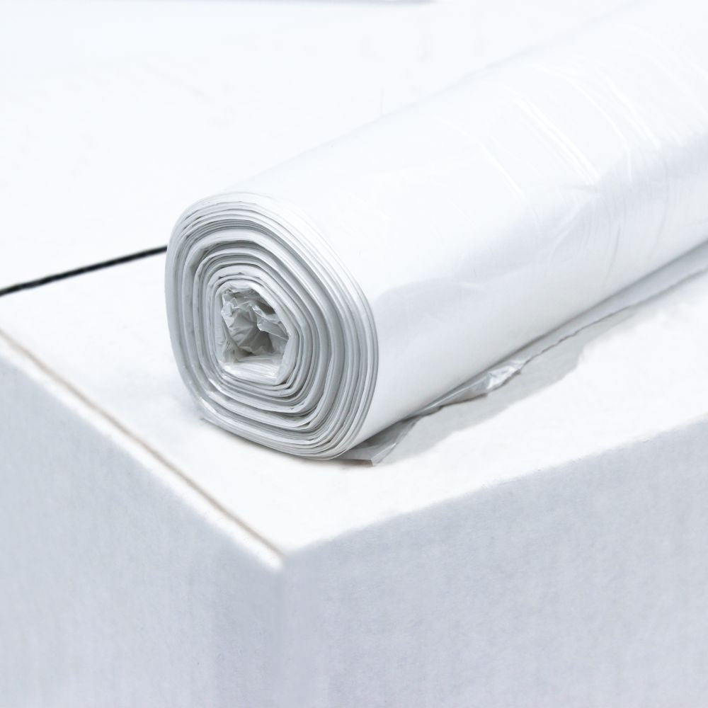 Rola DEISS HDPE vreciek na odpadky s objemom 20 litrov, 59906, biela od EMIL DEISS KG (GmbH + Co.) leží na okraji bielej plochy z recyklovaného materiálu. Vrecká sú úhľadne zvinuté a majú viacero vrstiev. Jednoduché biele pozadie zdôrazňuje textúru a vysokú elasticitu fólie plastu.