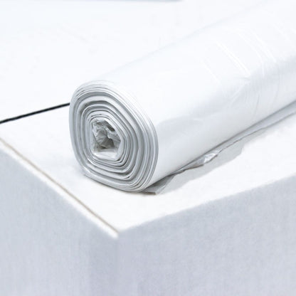 Rola DEISS HDPE vreciek na odpadky s objemom 20 litrov, 59906, biela od EMIL DEISS KG (GmbH + Co.) leží na okraji bielej plochy z recyklovaného materiálu. Vrecká sú úhľadne zvinuté a majú viacero vrstiev. Jednoduché biele pozadie zdôrazňuje textúru a vysokú elasticitu fólie plastu.