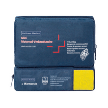 Modrá lekárnička s nápisom „Holthaus Mini Combi Verbandtasche Motorrad“ od Holthaus Medical GmbH & Co. KG s viacjazyčným textom pre motocykle. Zodpovedá norme DIN 13167 a obsahuje reflexnú vestu viditeľnú cez priehľadnú časť. Mini Combi Verbandtasche má dve priehradky na zips – jednu hore a jednu na boku.
