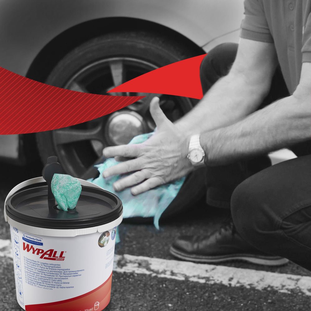 Osoba kľačí, aby očistila autokolesá so zelenými utierkami WypAll® od Kimberly-Clark GmbH. V popredí stojí viditeľný kontajner so 6 vedrami x 90 listov. Čierno-biele pozadie má výrazný červený grafický akcent.