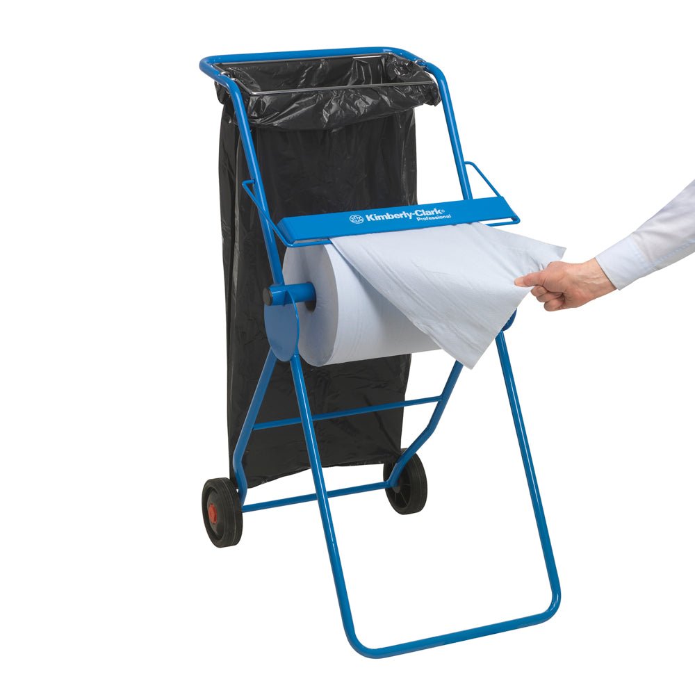 Vidieť je modrý dávkovač papierových uterákov s čiernym odpadkovým vreckom, zatiaľ čo ruka vytiahne list z veľkej rolky WypAll® X60 General Clean (1 rolka x 500 listov, modrá) od Kimberly-Clark GmbH - ideálne pre profesionálne čistiace úlohy.