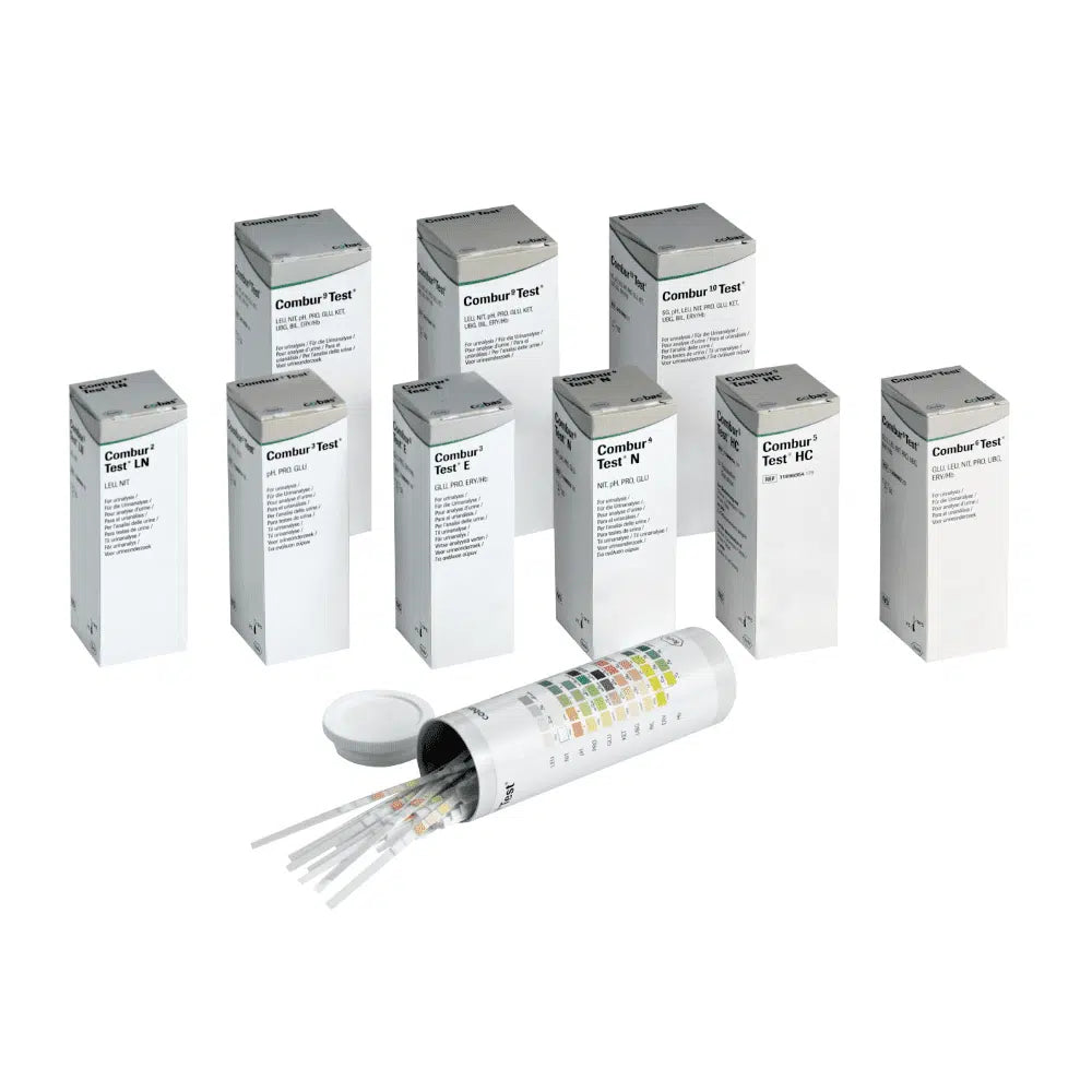 Za otvoreným valcovým kontajnerom s vekom sa skrýva deväť škatúľ s nápisom „Combur®“ od spoločnosti Servoprax GmbH, ktoré obsahujú po 100 Roche testovacích prúžkov na moč. Na boku kontajnera je pripevnená viacfarebná tabuľka, ktorá je ideálna na vykonanie rýchleho testu.
