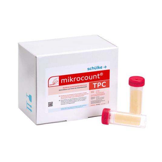 Biela škatuľka s nápisom „Schülke & Mayr GmbH Mikrocount® TPC, živná pôda | balenie (20 kusov)“ s logom a popisom produktu vedľa dvoch fľaštičiek na mikrobiálne testy, z ktorých jedna má žlté viečko a druhá priehľadné viečko.