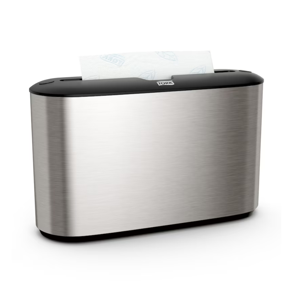 Tork Xpress® 460005 stolný dávkovač na skladané papierové utierky od Essity Professional Hygiene Germany GmbH sa vyznačuje elegantným dizajnom z nehrdzavejúcej ocele. Jeho strieborný kovový vzhľad je zvýraznený čiernym vrchom, z ktorého elegantne vyčnieva časť bielych papierových utierok. Ideálne pre používateľov skladaných papierových utierok, ktorí si cenia štýl aj funkčnosť.