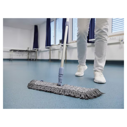 Osoba v bielych topánkach a nohaviciach utiera modrú podlahu v miestnosti so zatvorenými žalúziami a modrými závesmi pomocou Vileda GmbH Professional Swep Duo r-MicroCombi Mop - 50 cm. V blízkosti je skladací stôl a pod oknami je radiátor.