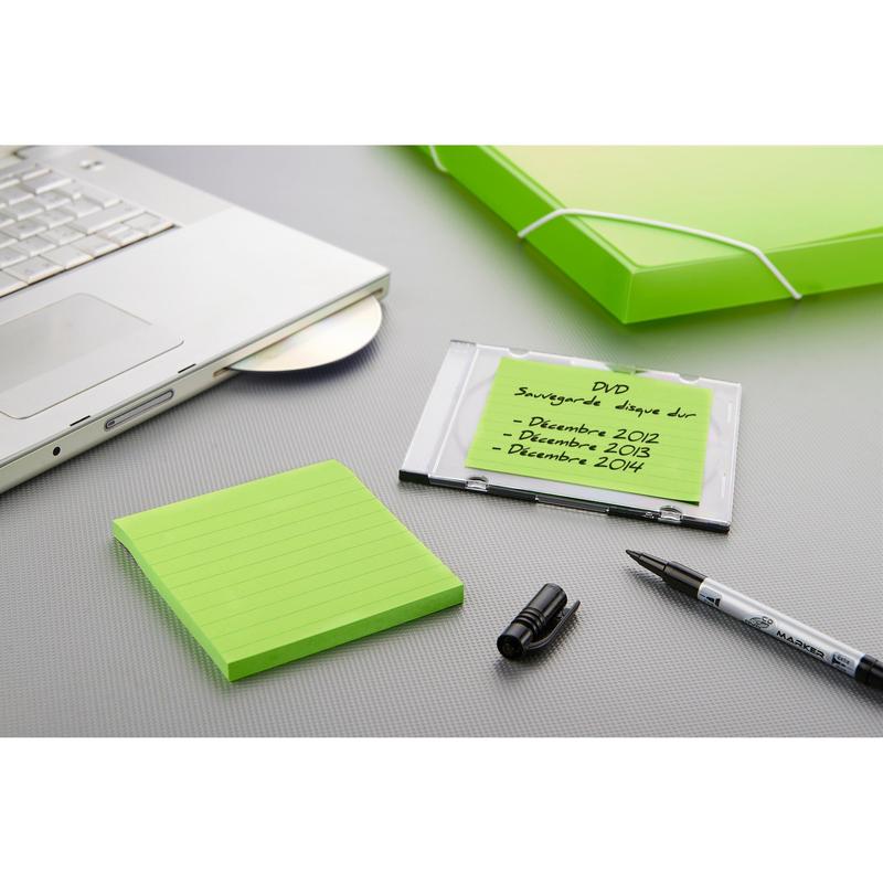 Notebook s otvorenou jednotkou, zelený zakladač, čierny fix bez vrchnáka, obal na DVD so španielskym popisom a Post-it® Super Sticky Notes od 3M Deutschland GmbH vo veľkom formáte (101 mm x 101 mm) ležia na šedej ploche.