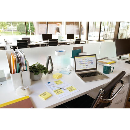 Moderná kancelária s laptopom, 3M Post-it® Notes (žlté, 76x76 mm, 100 listov/blok), šálkou, dokumentmi, rastlinami a príslušenstvom na bielom stole. V pozadí sú vidieť ďalšie stoly a veľké okná.