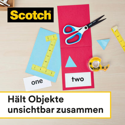 Na stole sú nožnice, meracie pásmo, obojstranná lepiaca páska Scotch® (balenie náhradných náplní, 2 role, 12 mm x 6,3 m) od 3M Deutschland GmbH a farebný papier s vystrihnutými tvarmi. Text znie "Drží objekty neviditeľne spolu."