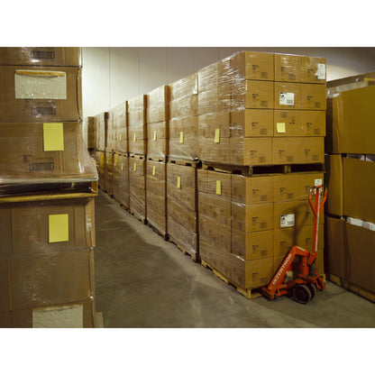 V sklade sú naskladané Post-it® Super Sticky Notes vo veľkom formáte, Ultra Žltá (101 x 152 mm, 90 listov/blok, 6 blokov), od 3M Deutschland GmbH, zabalené na paletách. Vedľa stojí červený ručný paletový vozík.