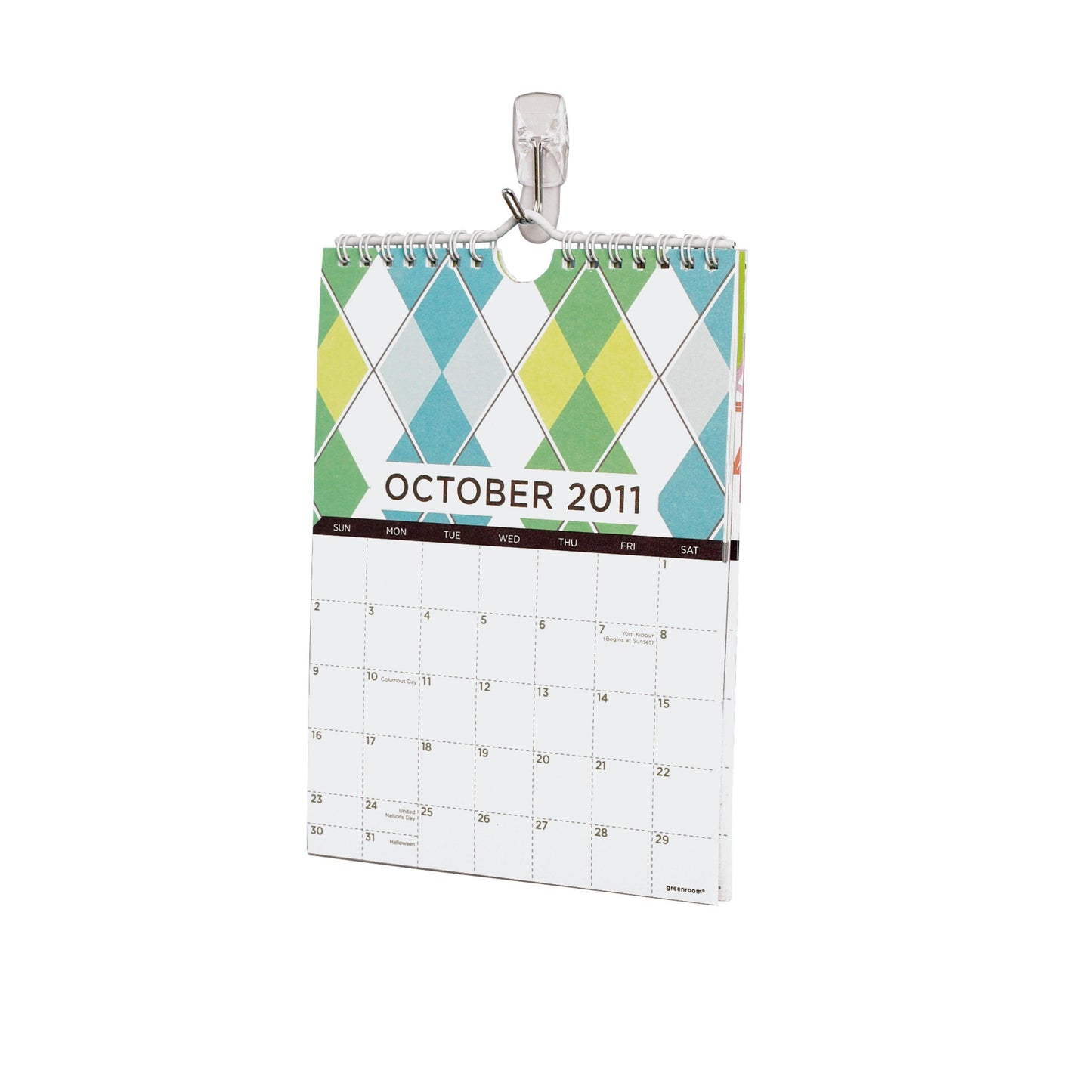 An einem weißen Wandhaken hängt ein kleiner, spiralgebundener Wandkalender bis Oktober 2011 mit buntem Rautenmuster: der Command™ Drahthaken, klein, transparent, mit transparenten Strips von 3M Deutschland GmbH.
