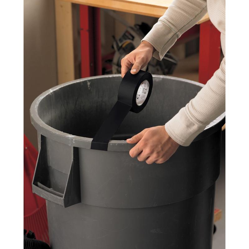 Osoba lepí pásku Scotch® Extremium™ Universal (3 m x 19 mm) od 3M Deutschland GmbH cez vrch veľkého sivého odpadkového koša a upevňuje ju na protiľahlých stranách okraja. V pozadí sú viditeľné pracovný stôl a náradie.